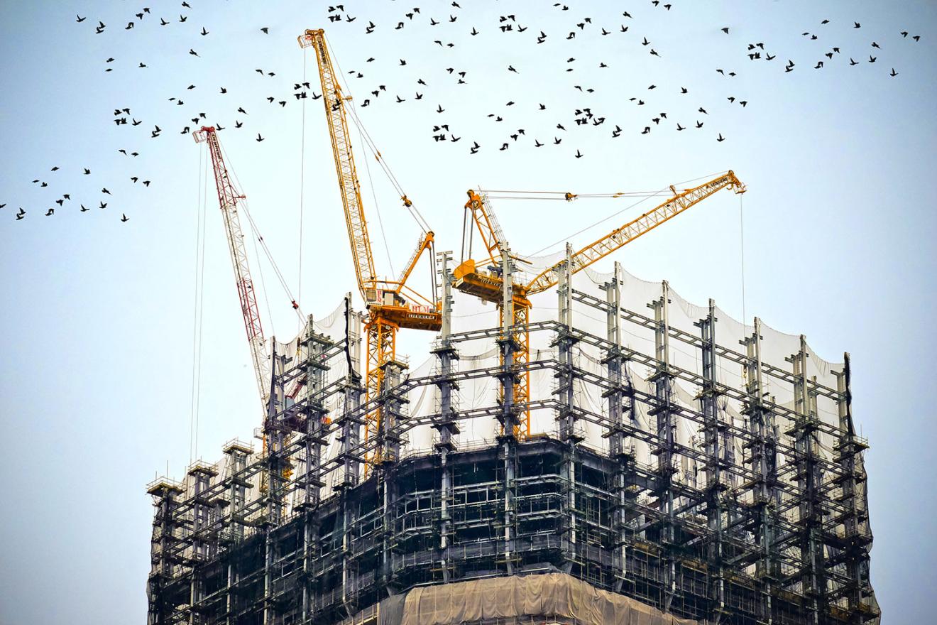 3 cranes on building being constructed