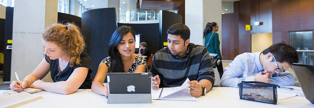 Four students talking and working at a desk