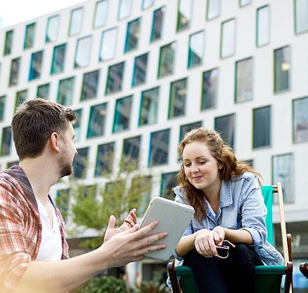 Students talking and looking at IPAD outside science building