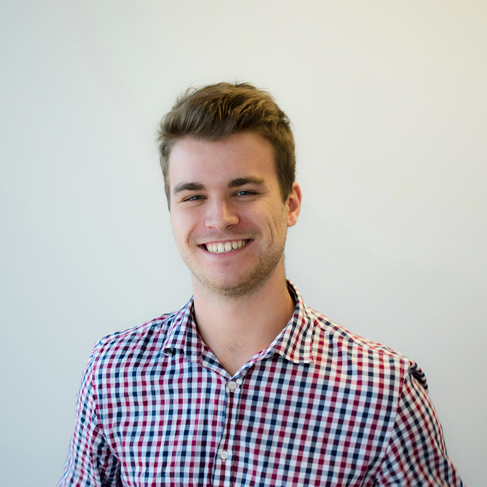 Headshot of Daniel, standing in front of a white wall