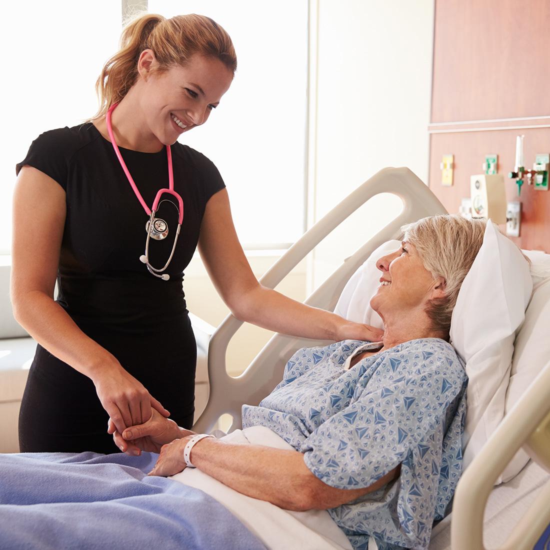 Nurse standing by a patient in a hospital bed