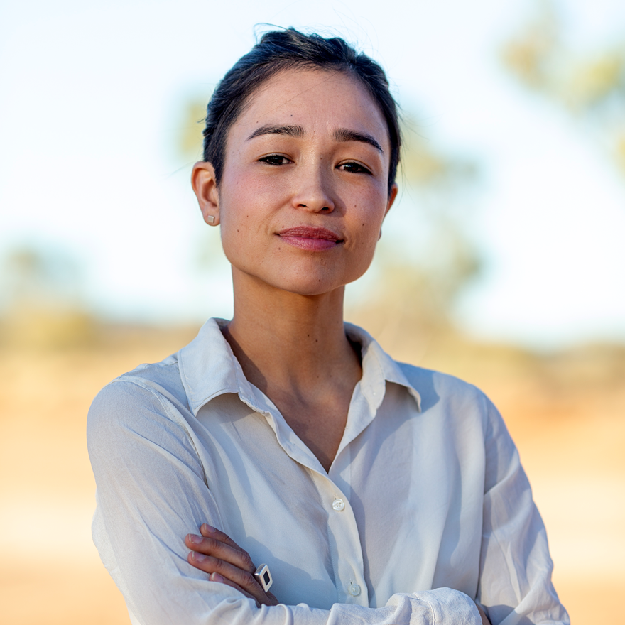 Maya Newell smiling at the camera with her arms folded across her chest