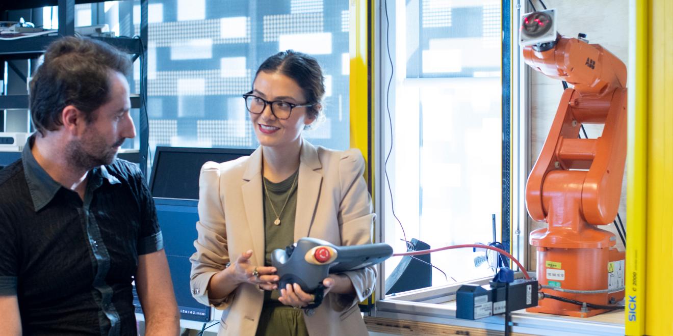 A woman demonstrates a robotic arm to a man