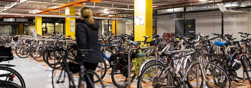A person walking a bike into a room full of bikes
