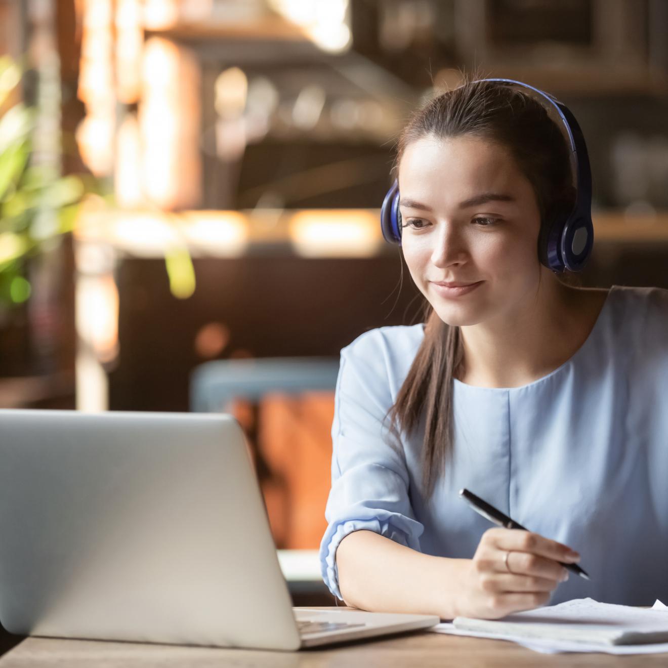 A female student taking notes during an online presentation