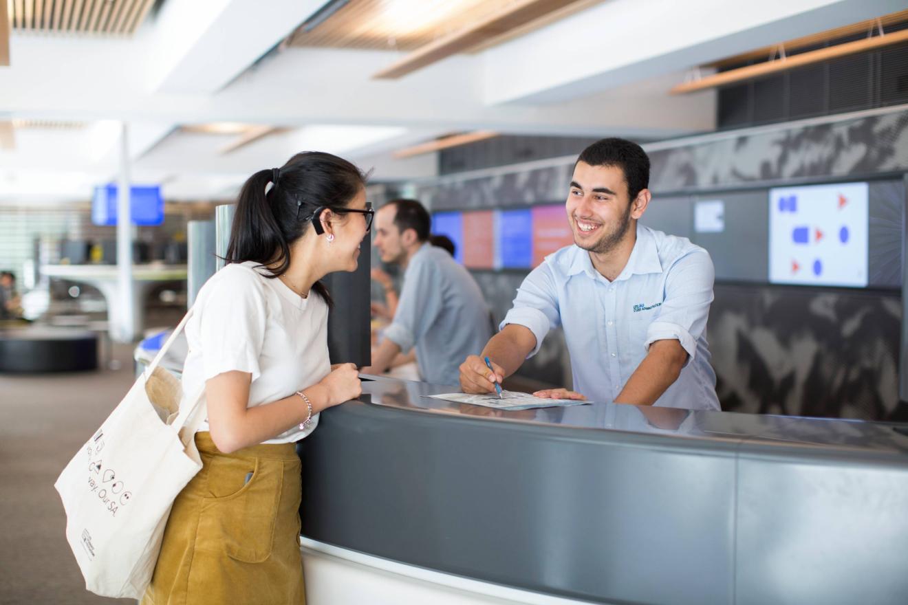 Young man behind the counter talking to a student