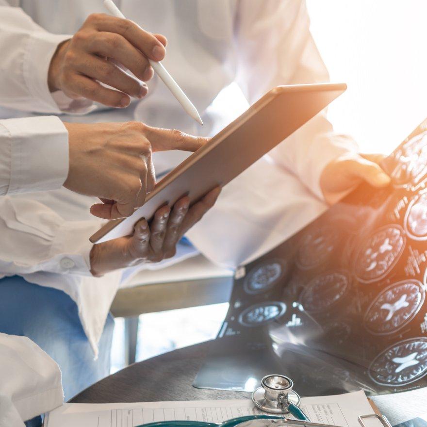 Doctors looking at brain scan and tablet device
