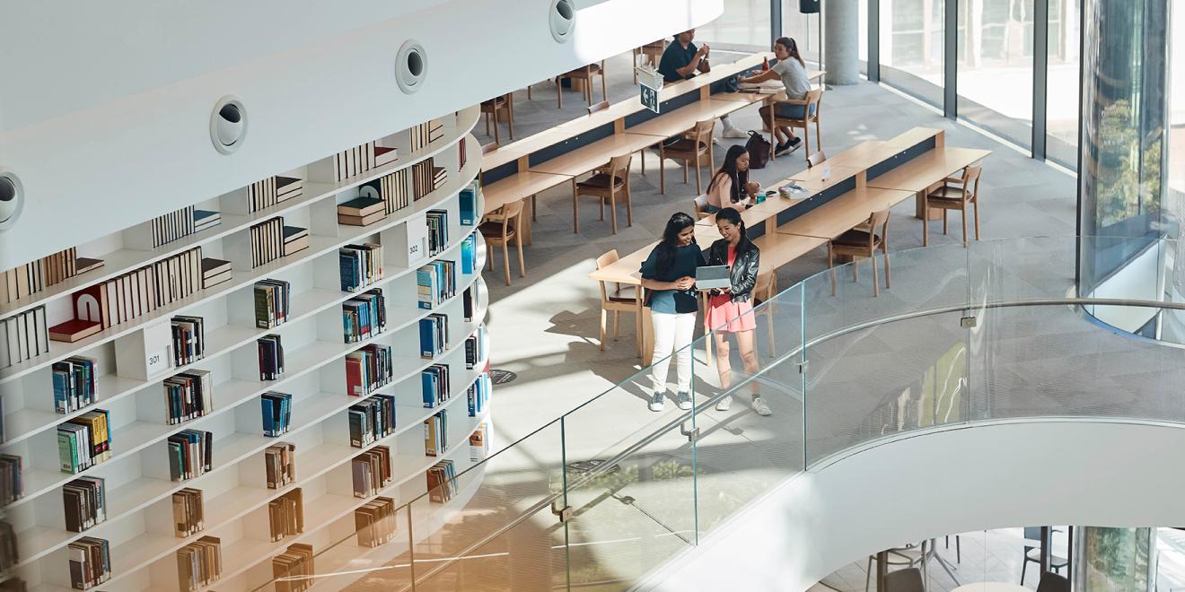 Two students standing while sharing a laptop in a modernised UTS Library