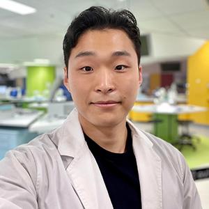 A portrait shot of UTS graduate Kenny Paek wearing a science lab coat