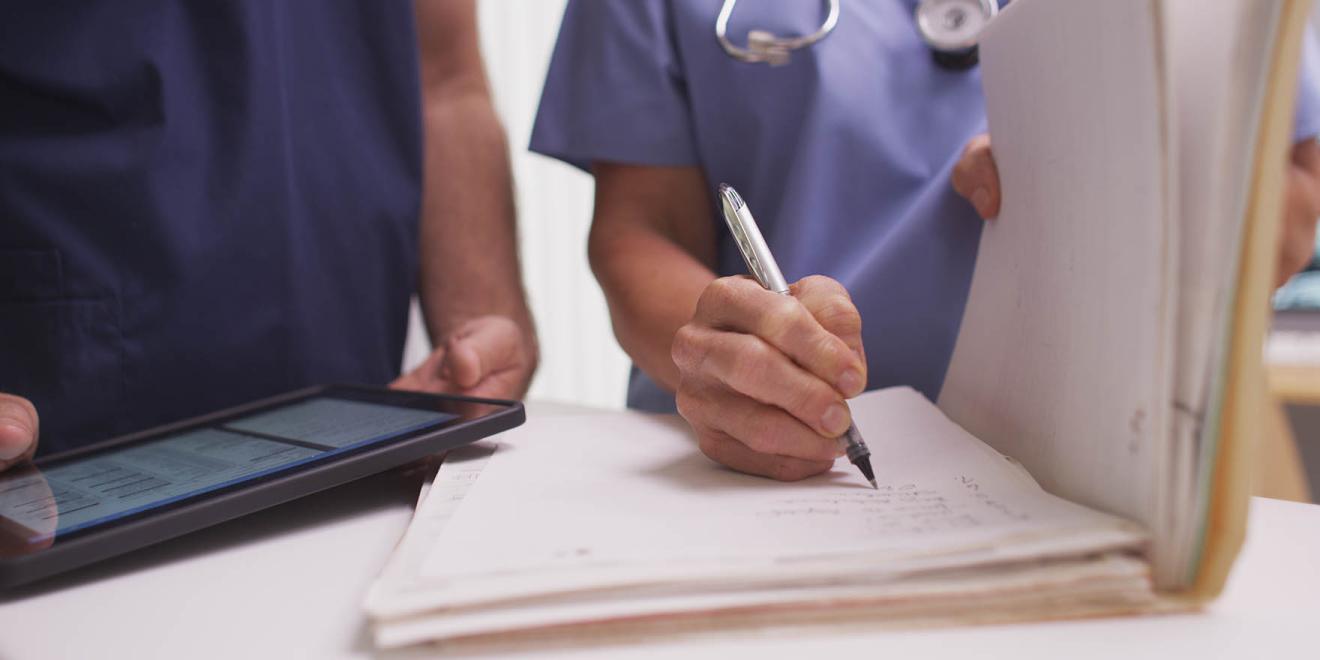 Nurse writing notes in file