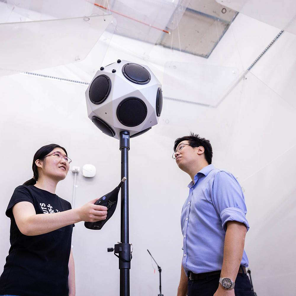CAAV researchers taking acoustic measurements in a reverberation room. The multidirectional speaker is shaped like a soccer ball and is mounted on a stand.