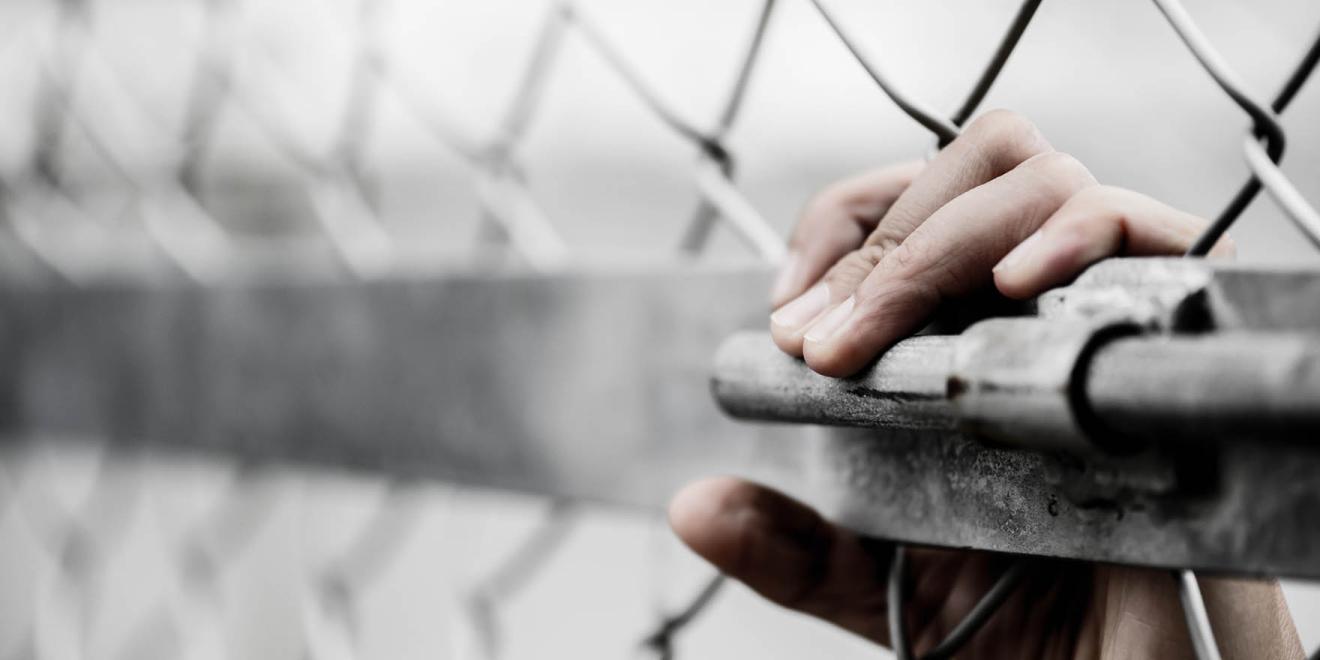 Hands holding latch of metal gate