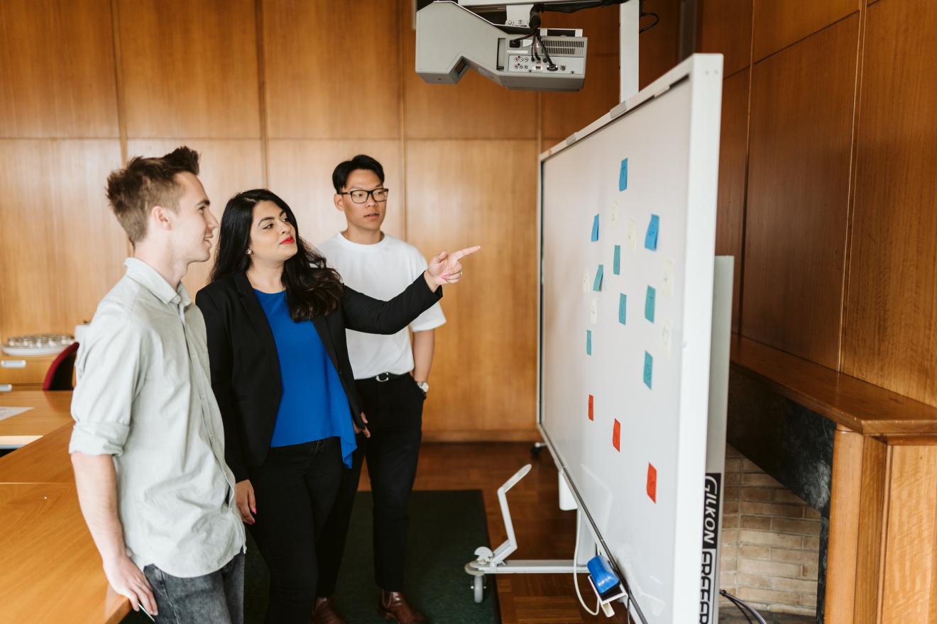 Three people looking at a white board