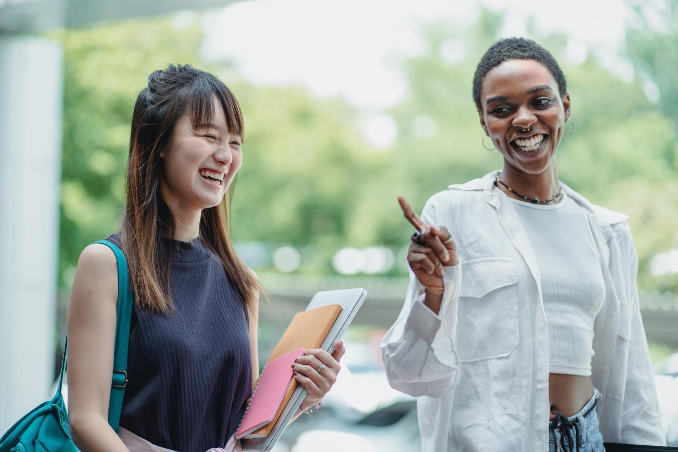 Two students talking and laughing as they walk.