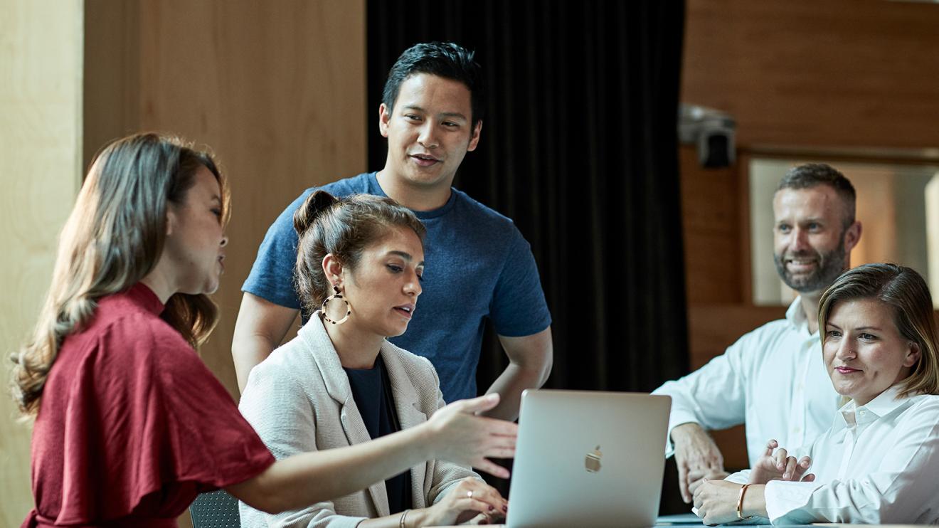 Five people in a discussion around a laptop