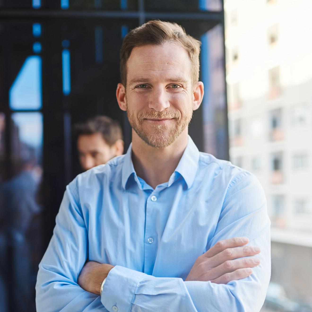 Person in blue shirt standing with folded arms