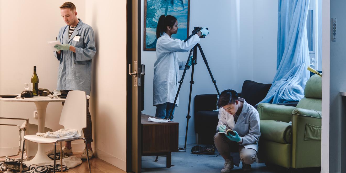 Three students assessing a mock crime scene in the UTS Crime Scene Simulation Lab