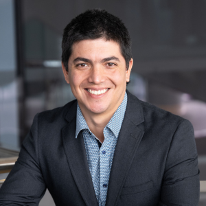 Roman Marchant, light blue collar shirt with a dark suit jacket, black short hair, male, smiling