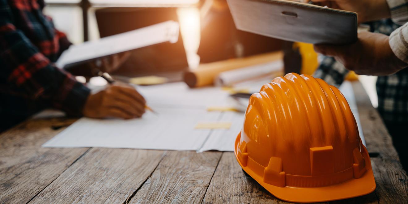 People working together in office with a construction hat on a desk