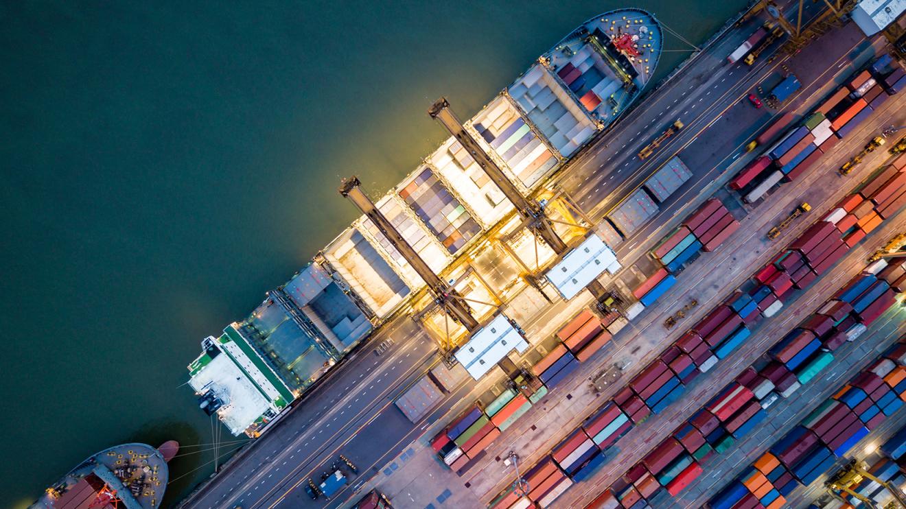 Top view of international port with Crane loading containers in import export business logistics at night