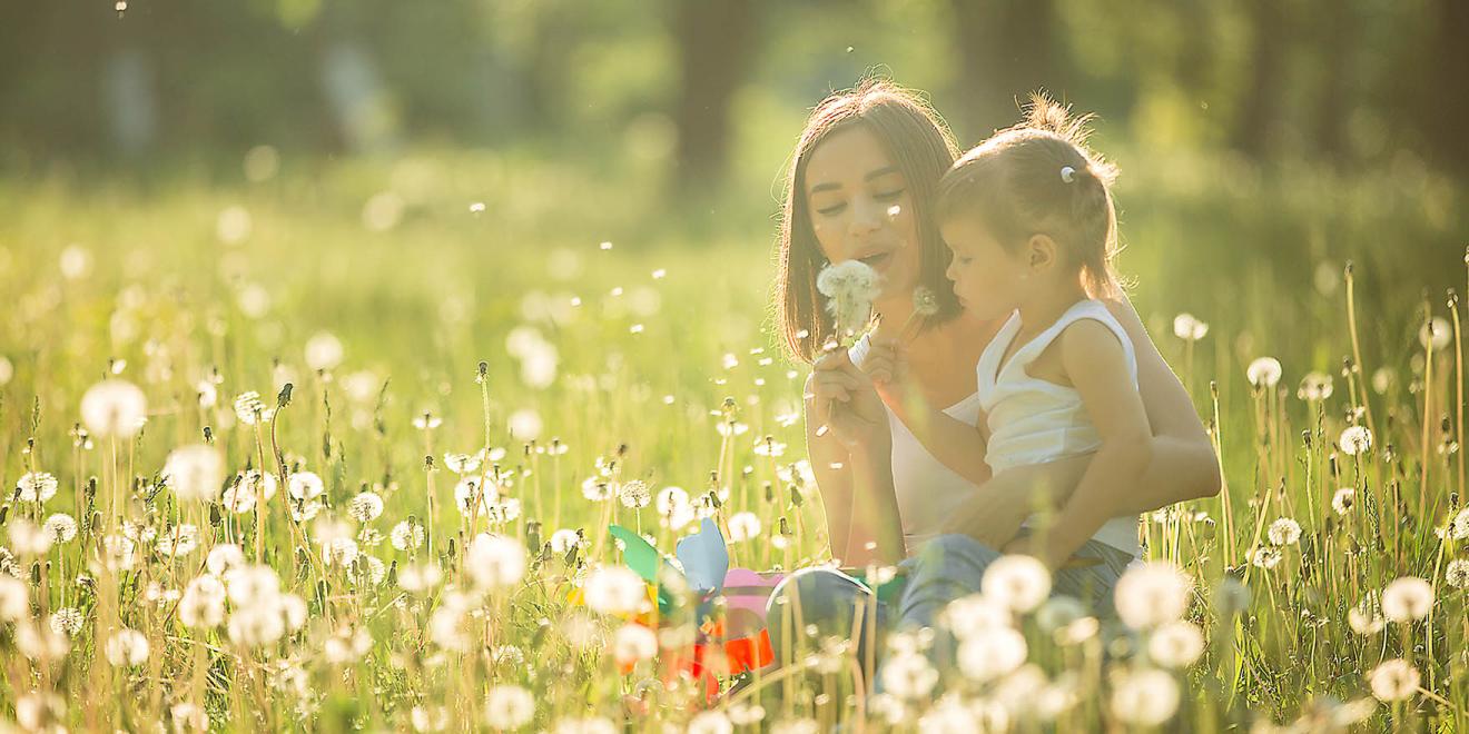 Young mother and her little child playing in the park at summer time.