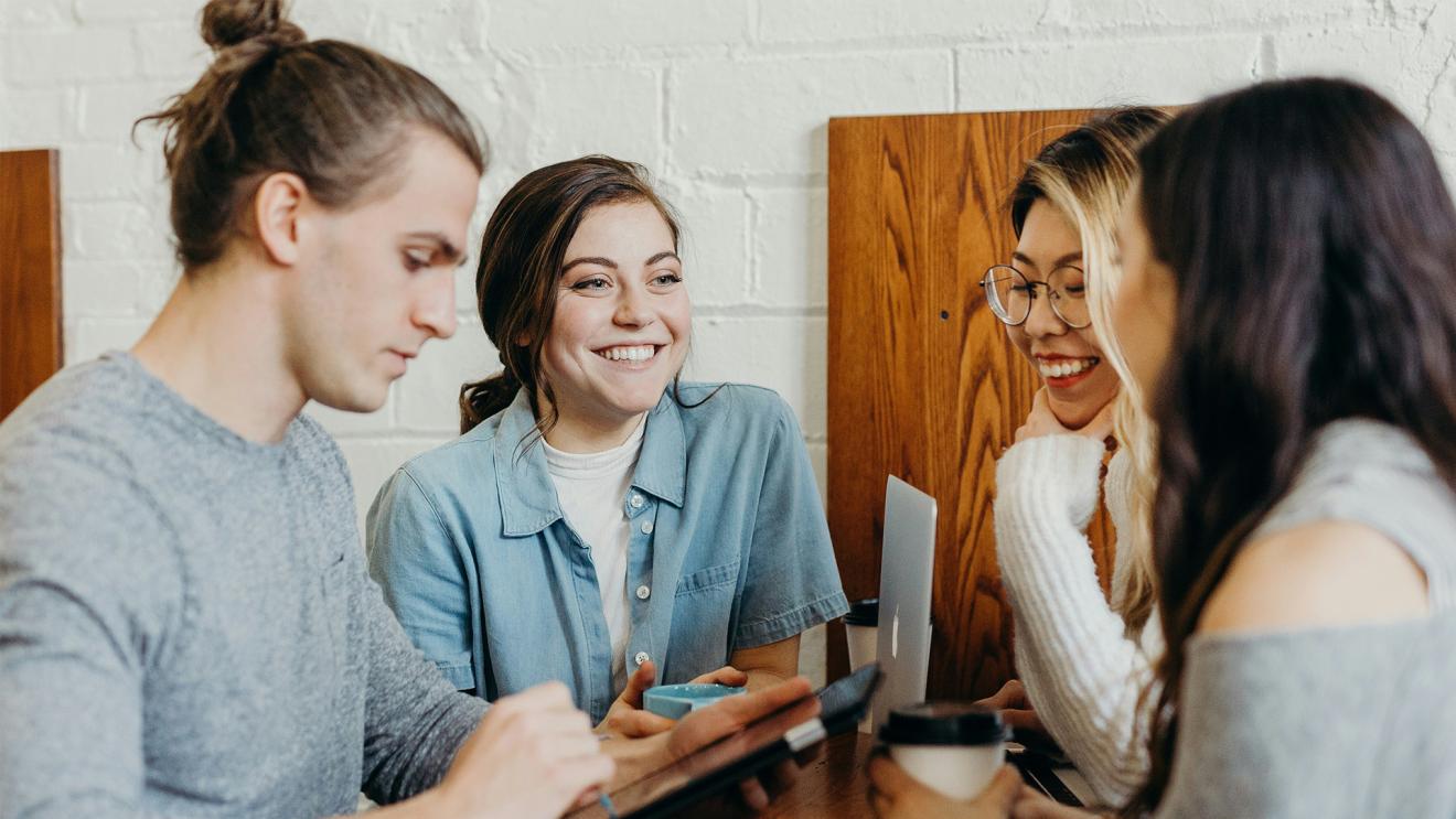 Four students sitting at a table smiling and discussing study options