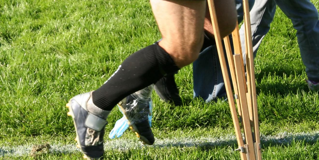 Rugby player walking off the pitch using crutches