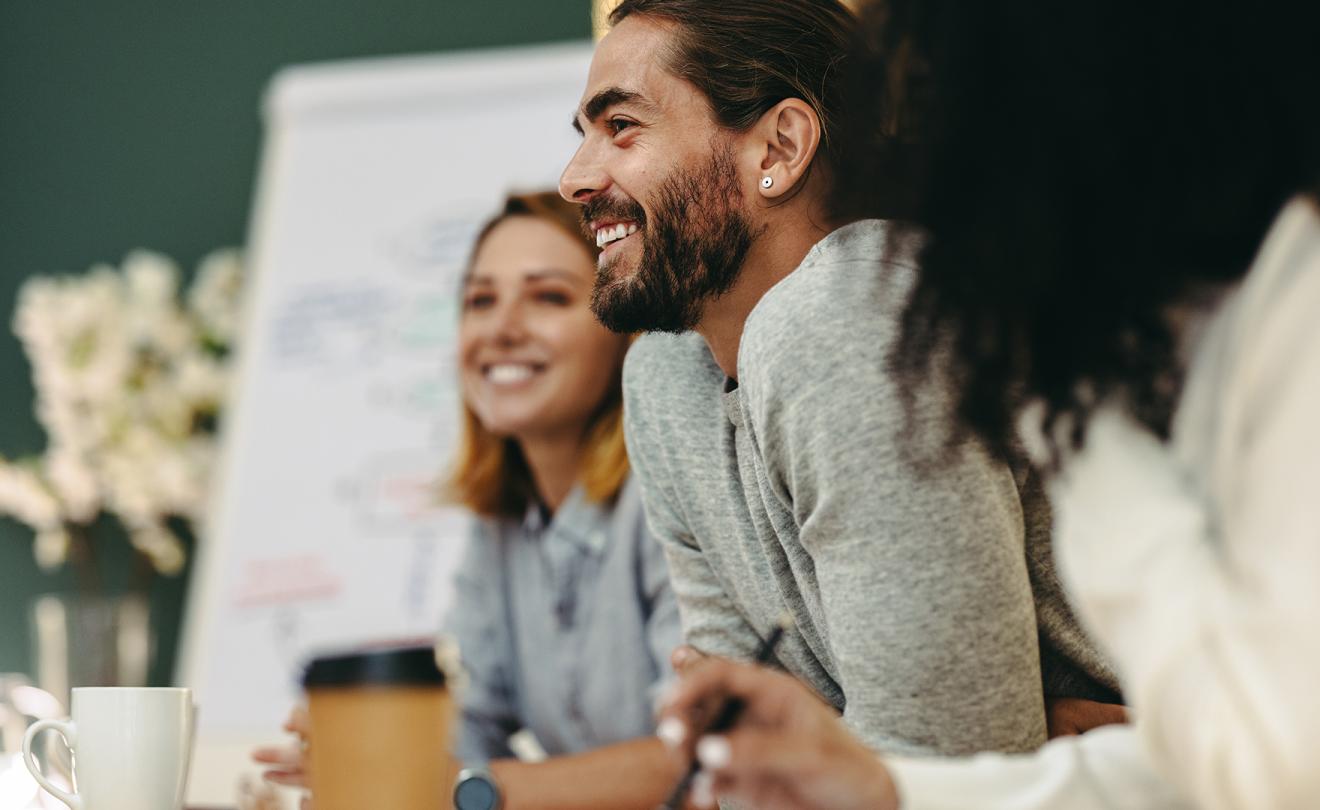 Happy young businessman attending a meeting with his team