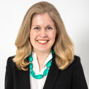 Woman with long hair, wearing jacket and green necklace