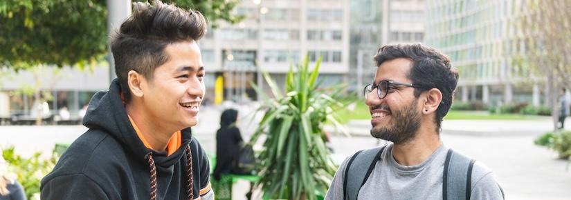 2 young men are talking and smiling