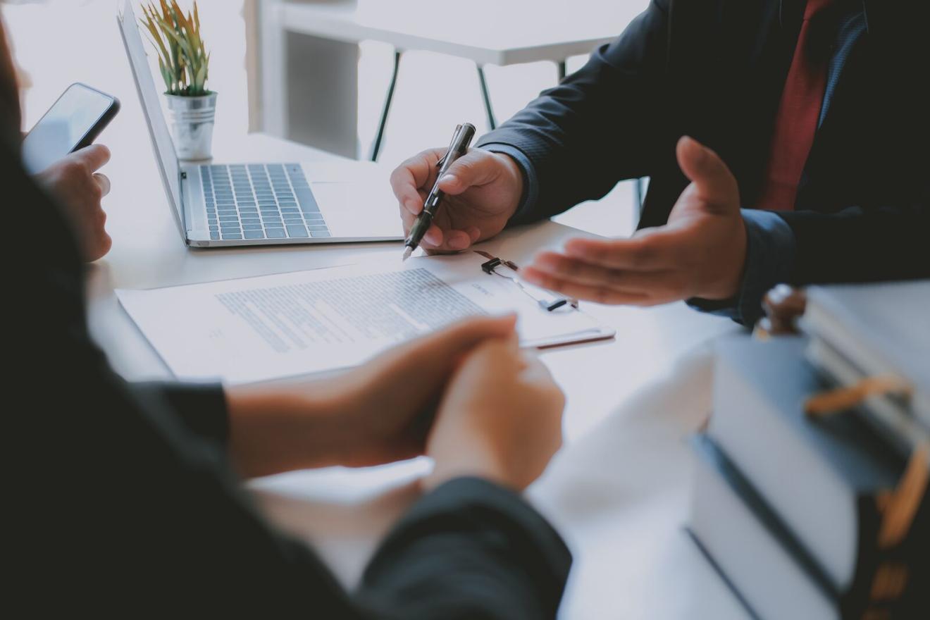 Image of a male with a pen showing two people a document on a clipboard
