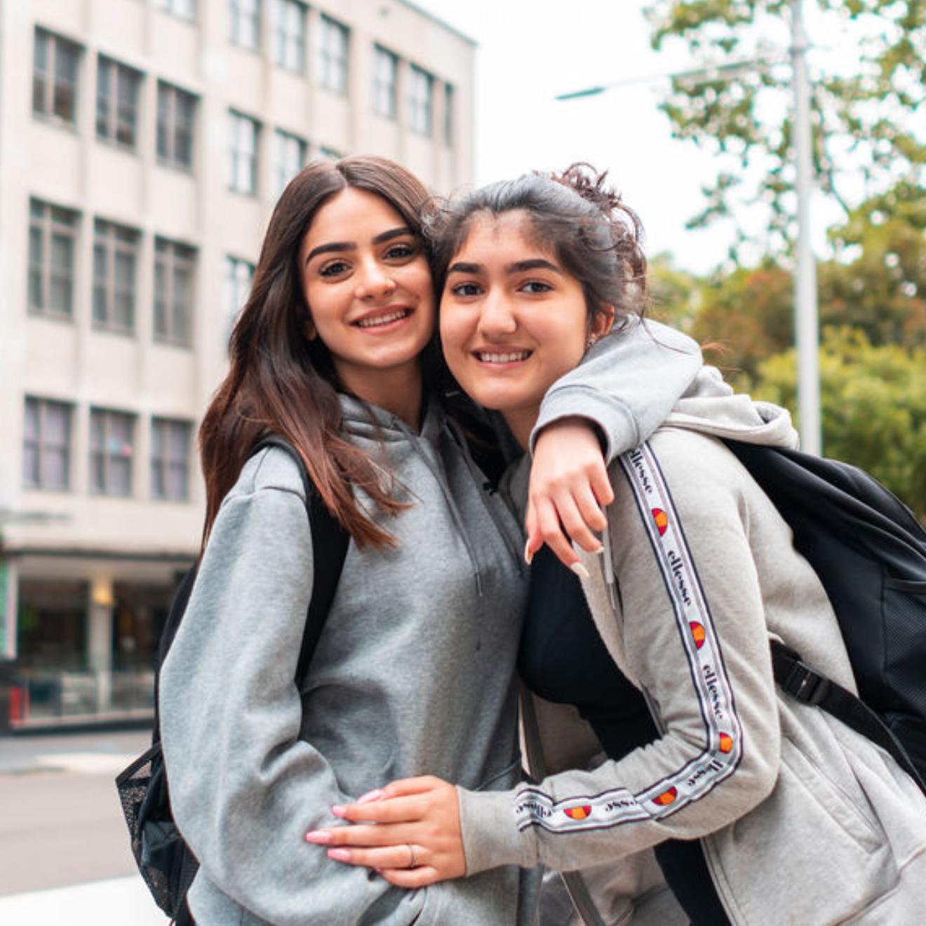 Two female high school students embracing