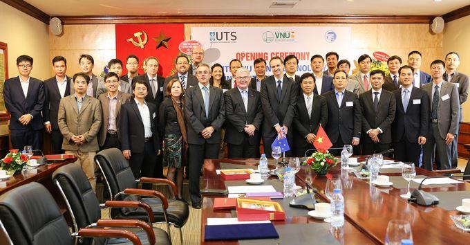 A large group of people pose for a photo in front of a banner and behind a long table