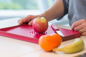 Sophie Marmont using a bright, fashionable non-slip cutting board design by Joseph Joseph