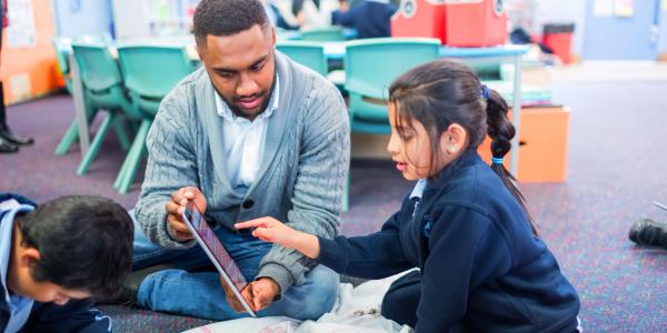 Children and their teacher interacting with technology