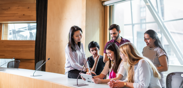 International students gather around an ipad, in the Business School building