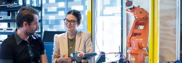 A woman demonstrates a robotic arm to a man