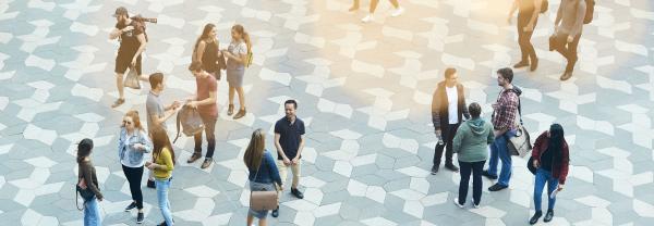 Arial view of clusters of students chatting on the Alumni Green paving