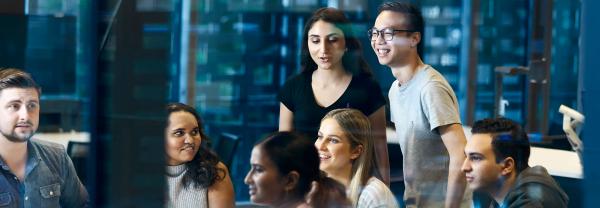 Seven students gathered together chatting in a classroom