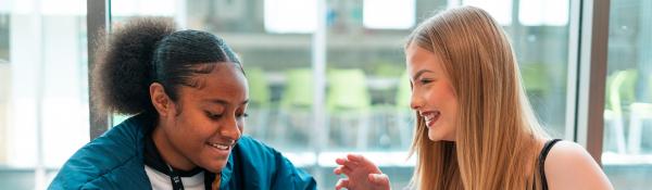 Two young women talking and smiling.