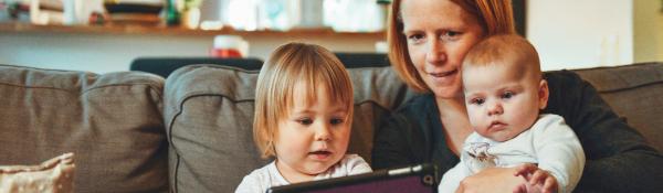 Parent and two babies reading a tablet