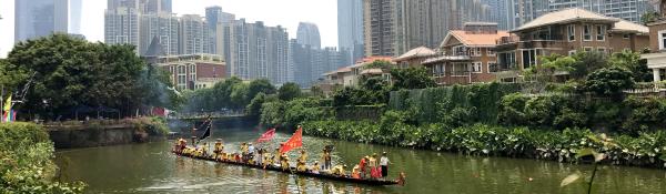 Traditional boat, meandering river, city backdrop