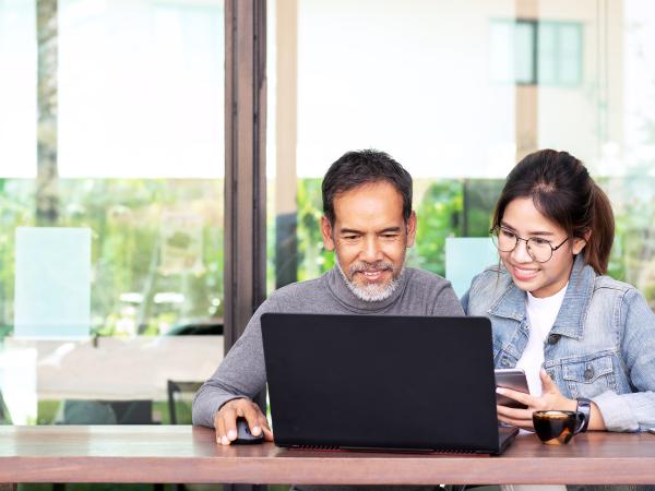 Younger student and older man looking at computer