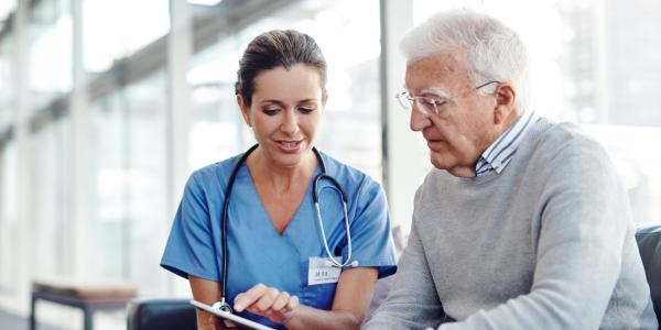 Nurse showing older man his results on a tablet computer
