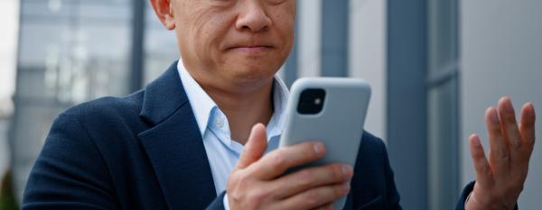 A confused elderly man looking at a phone screen