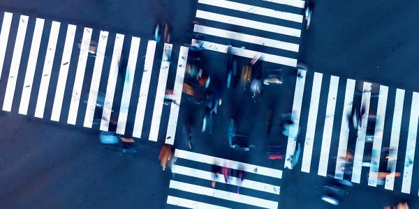 An aerial image of people walking across a pedestrian crossing at an intersection 