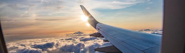 Image of a wing of a plane and the sun, shot through the window