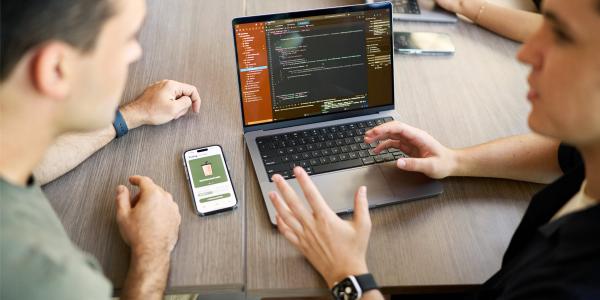 Two people having a discussion with their laptop and phone on the table in the background