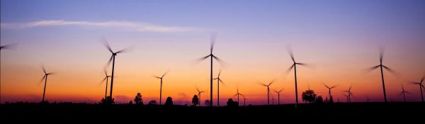 A view of a windfarm at sunset with a blue sky and bright orange horizon