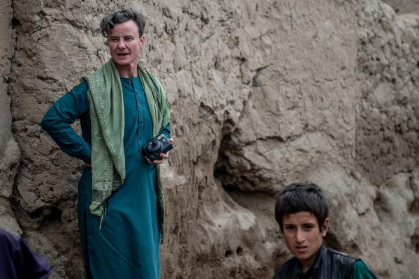 Jordan Bryon, in traditional Afghan robes, stands on a rock